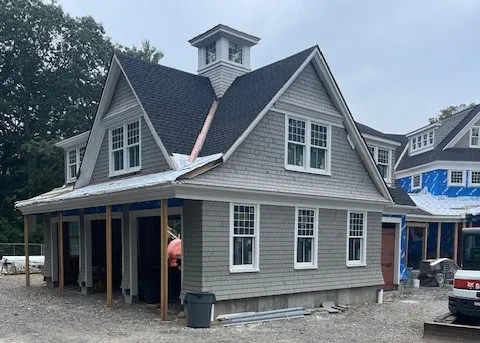 Gray shingle-sided home with cupola under construction